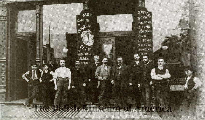 图片描绘的是位于芝加哥西分区街1414(当时是112)的Zgoda印刷店和PNA大楼入口前的工人;1889.